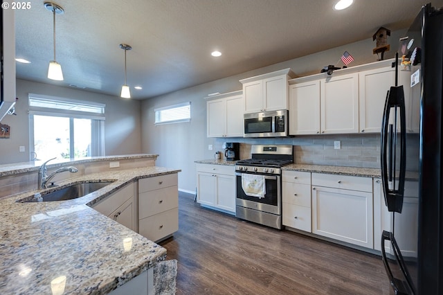 1531 Washington St, Independence, OR 97351 - kitchen with appliances with stainless steel finishes, a sink, white cabinets, hanging light fixtures, and dark wood-style floors