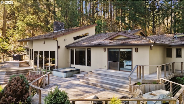 back of property with a wooden deck, a chimney, and stairway