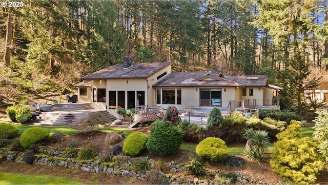 rear view of property featuring a wooden deck and stucco siding