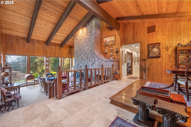 living room with visible vents, beam ceiling, and wood walls