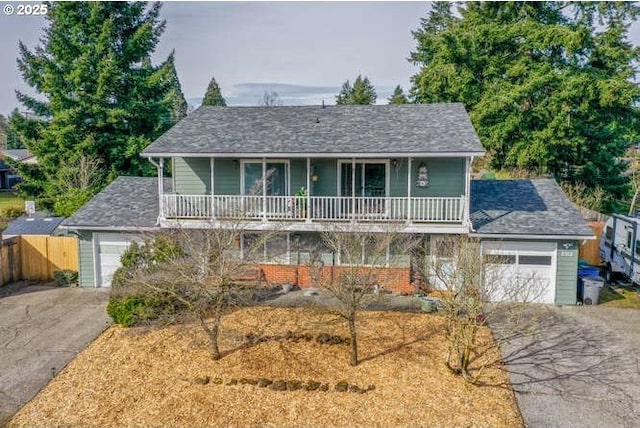 view of front of property featuring an attached garage, driveway, a balcony, and fence