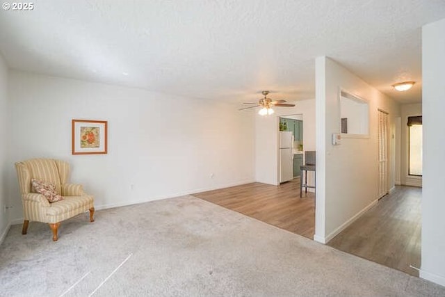 unfurnished room featuring carpet flooring, a textured ceiling, a ceiling fan, and wood finished floors