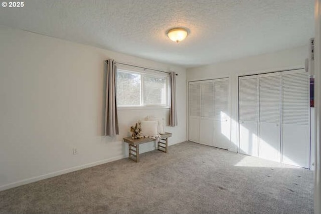 unfurnished bedroom featuring carpet, two closets, and a textured ceiling