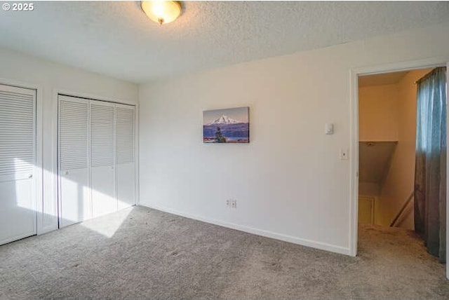 unfurnished bedroom with multiple windows, baseboards, carpet floors, and a textured ceiling