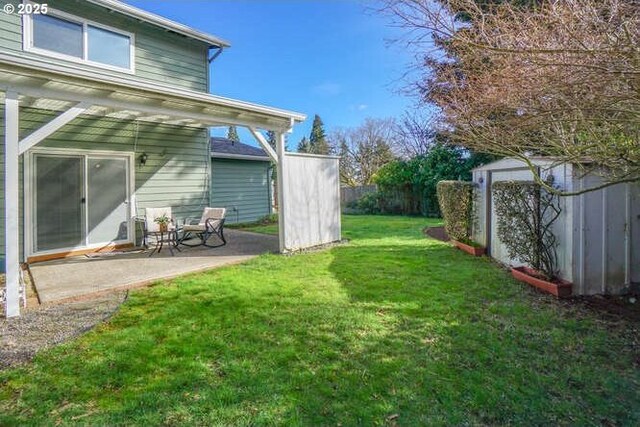 view of yard with an outbuilding, a storage unit, a patio area, and fence