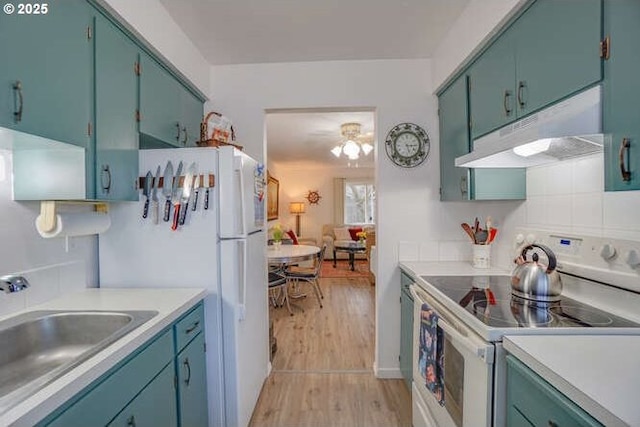 kitchen with white appliances, a sink, light countertops, under cabinet range hood, and light wood-type flooring