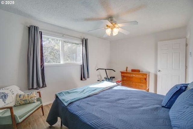 bedroom with a textured ceiling, wood finished floors, and a ceiling fan