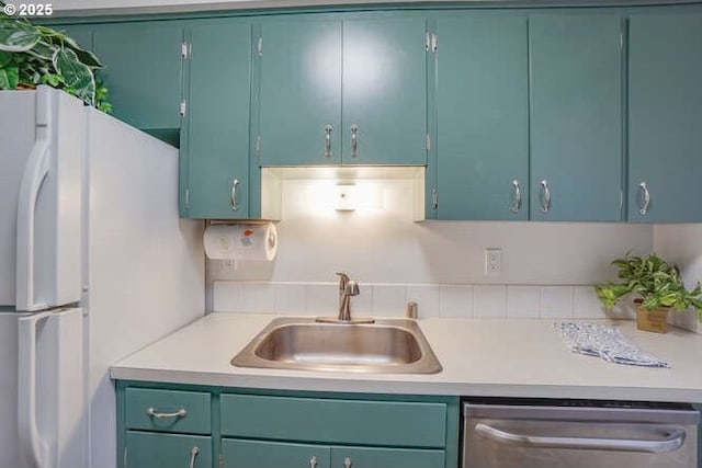 kitchen featuring a sink, dishwasher, light countertops, and freestanding refrigerator