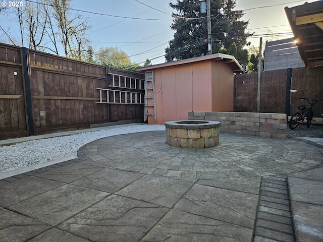 view of patio / terrace with a fire pit, a storage shed, an outbuilding, and a fenced backyard