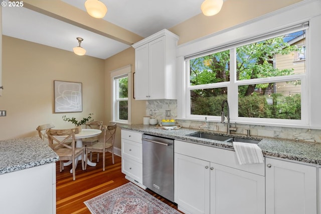 kitchen with stainless steel dishwasher, a sink, wood finished floors, tasteful backsplash, and white cabinetry