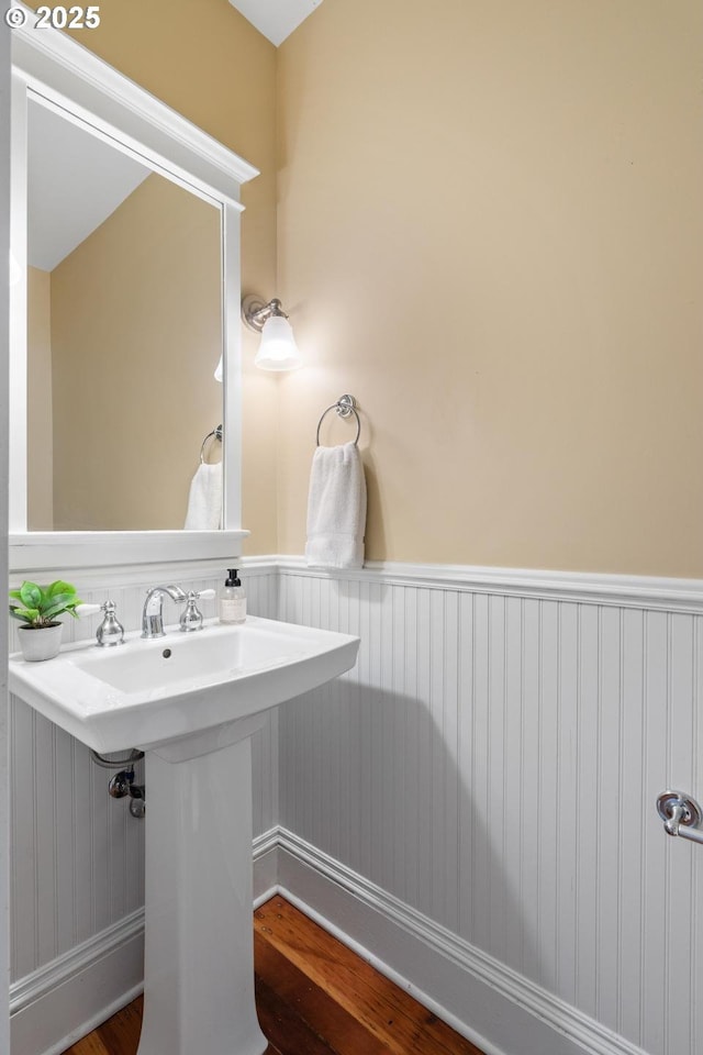 bathroom featuring a wainscoted wall and wood finished floors