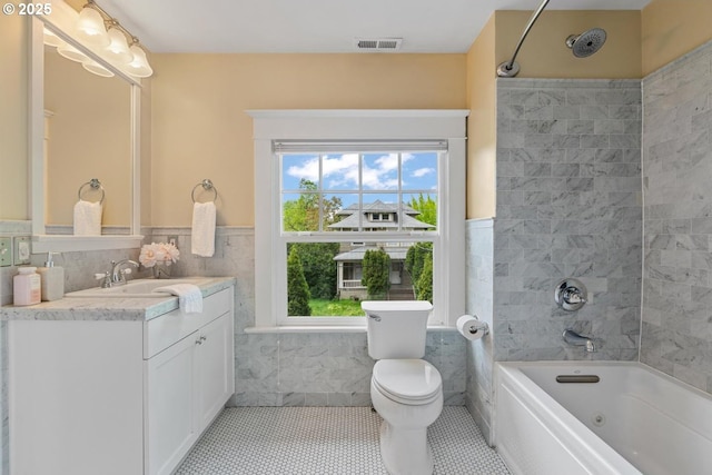bathroom with tile walls, plenty of natural light, bathtub / shower combination, tile patterned floors, and wainscoting