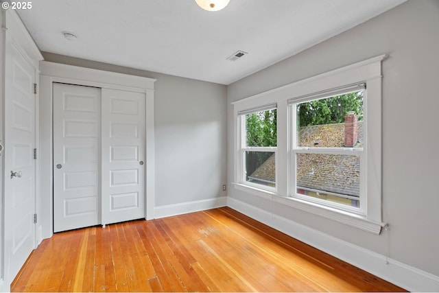 unfurnished bedroom featuring baseboards, light wood finished floors, and a closet