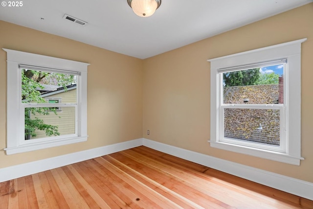 spare room with healthy amount of natural light, baseboards, and hardwood / wood-style flooring