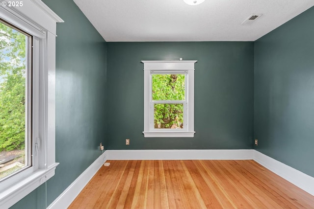 unfurnished room featuring healthy amount of natural light, wood-type flooring, and baseboards