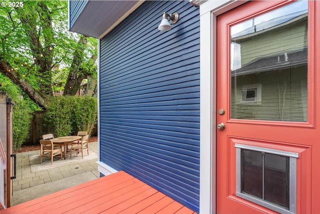 view of exterior entry featuring outdoor dining area, a patio area, and fence