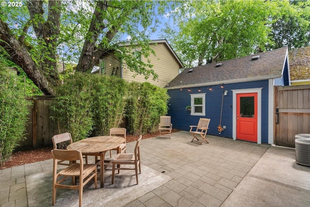 view of patio featuring fence, outdoor dining area, and central AC unit