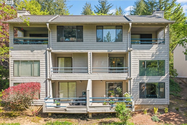 rear view of property with a chimney and a balcony