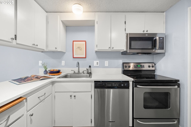 kitchen featuring light countertops, a sink, a textured ceiling, and stainless steel appliances