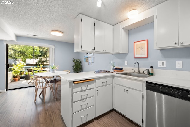 kitchen featuring stainless steel dishwasher, a peninsula, light countertops, a textured ceiling, and a sink