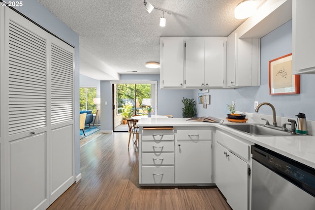 kitchen featuring a textured ceiling, stainless steel dishwasher, rail lighting, wood finished floors, and a sink