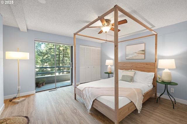 bedroom with visible vents, baseboards, a textured ceiling, and wood finished floors