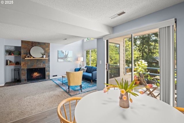 interior space with a textured ceiling, visible vents, wood finished floors, and a fireplace