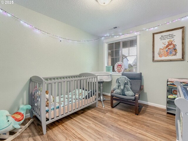 3190 Lily Ln, Mcminnville, OR 97128 - bedroom with wood finished floors, baseboards, a textured ceiling, and a crib