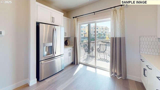 kitchen with tasteful backsplash, light hardwood / wood-style floors, stainless steel fridge with ice dispenser, and white cabinets