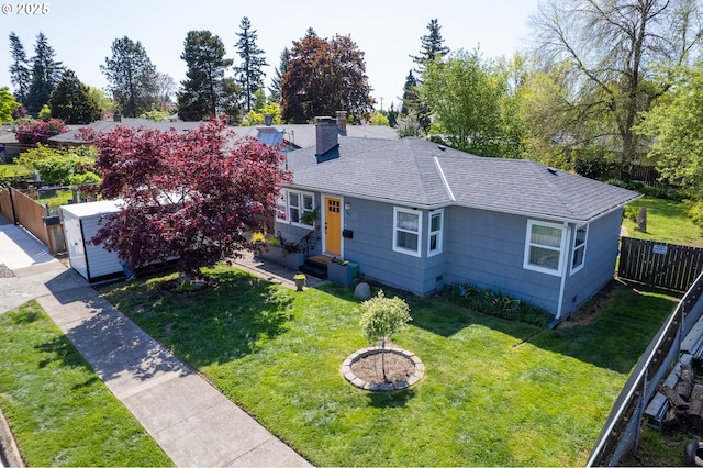view of front of property with a shingled roof, a front lawn, fence, and a chimney