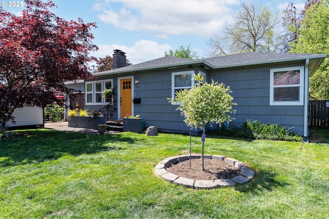view of front of home featuring a shingled roof, fence, a front yard, and a chimney