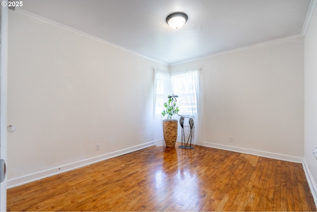 empty room featuring baseboards, ornamental molding, and wood finished floors