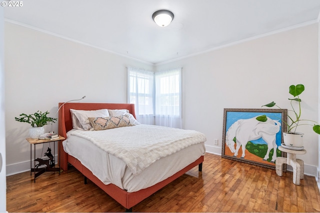 bedroom with crown molding, baseboards, and hardwood / wood-style flooring