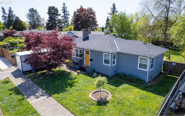 view of front facade featuring fence, a shingled roof, a front yard, entry steps, and a chimney