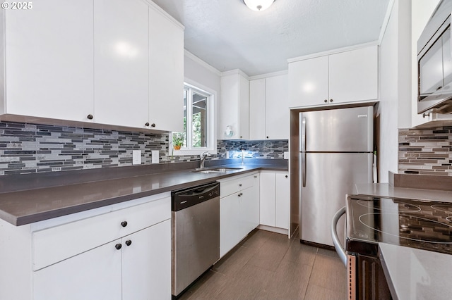kitchen with a sink, appliances with stainless steel finishes, tasteful backsplash, and white cabinetry