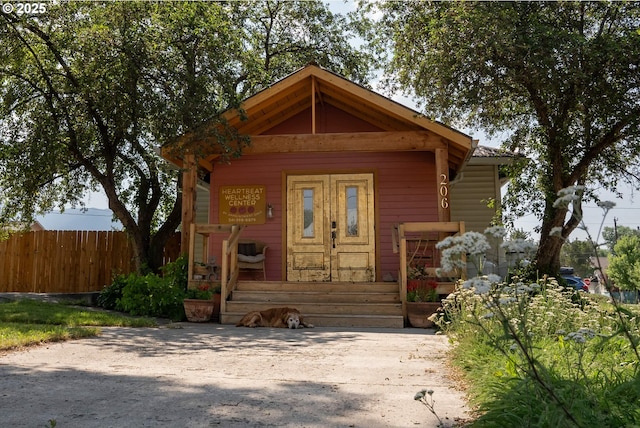 view of outdoor structure featuring a porch and fence