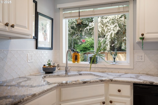 kitchen view of dishwasher, tasteful backsplash, and light stone countertops