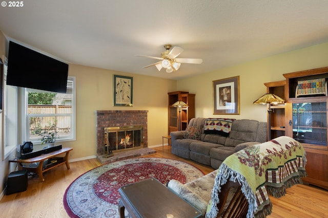 living area featuring wood finished floors, ceiling fan, a fireplace, and baseboards