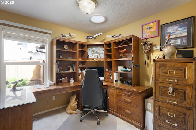 office space featuring a textured ceiling, built in study area, and light colored carpet