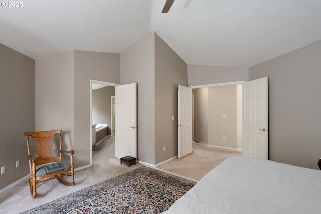 bedroom featuring light carpet, baseboards, ceiling fan, and ensuite bath