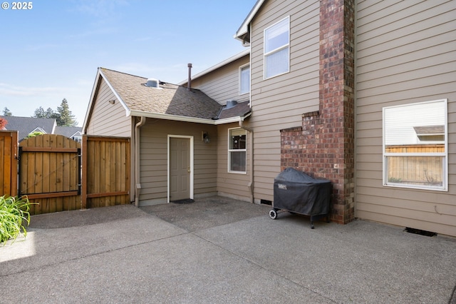 rear view of house with a gate, a patio, and a shingled roof