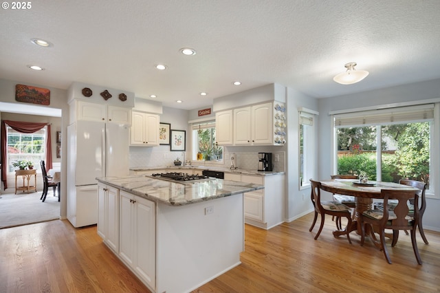 kitchen with freestanding refrigerator, light wood-type flooring, white cabinetry, stainless steel gas stovetop, and recessed lighting