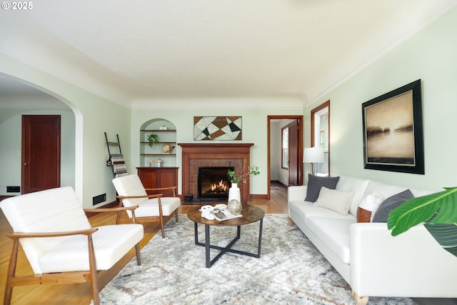 1830 N Winchell St, Portland, OR 97217 - living area with arched walkways, built in features, a fireplace, and wood finished floors