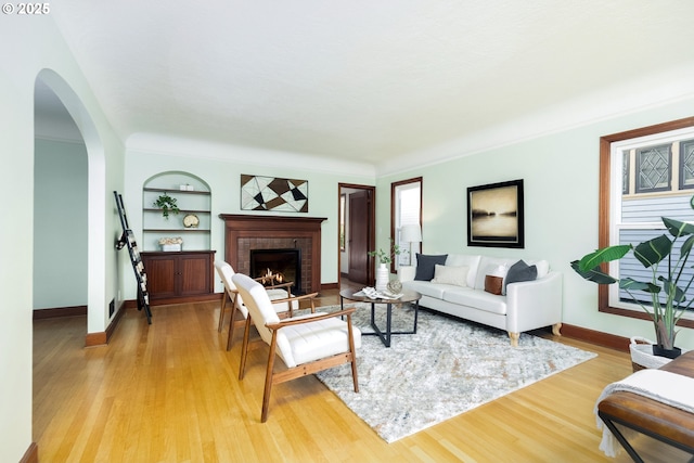 1830 N Winchell St, Portland, OR 97217 - living area featuring arched walkways, a brick fireplace, built in features, and light wood-style flooring