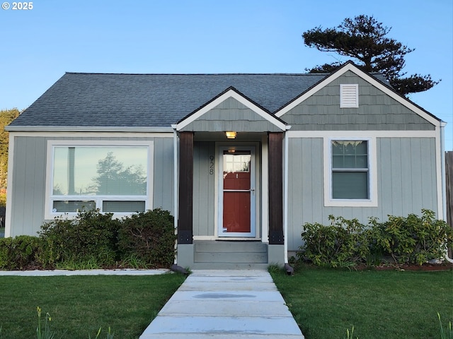 view of front of home with a shingled roof and a front yard