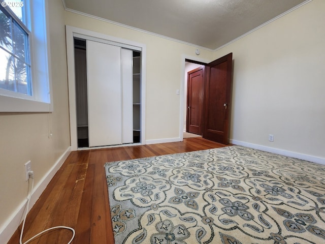 bedroom with ornamental molding, a closet, baseboards, and wood finished floors