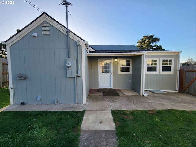 back of property with fence, a patio, and a lawn