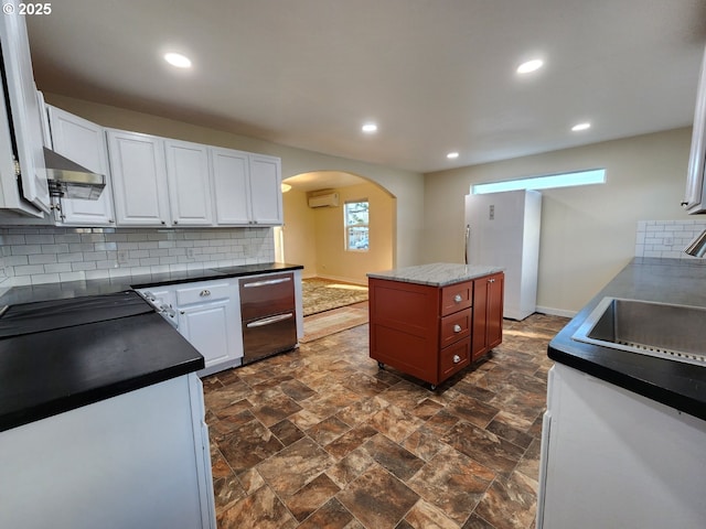 kitchen with tasteful backsplash, arched walkways, white cabinets, a wall unit AC, and dark countertops