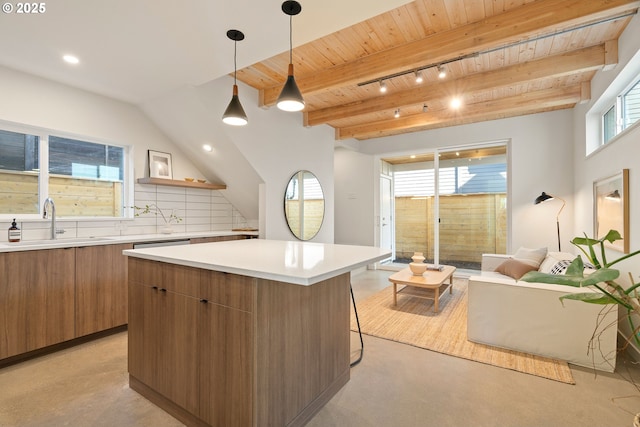 kitchen featuring finished concrete floors, decorative backsplash, brown cabinets, modern cabinets, and a sink