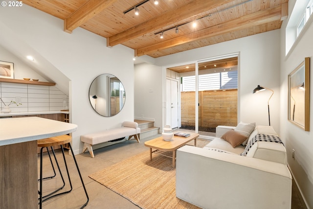 living area with concrete floors, beamed ceiling, wood ceiling, and rail lighting